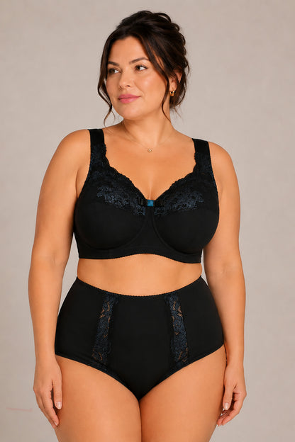 A plus size woman modeling a black lingerie set consisting of a wide strap cotton bra with lace trim and matching high-waisted cotton briefs with lace details panels. 