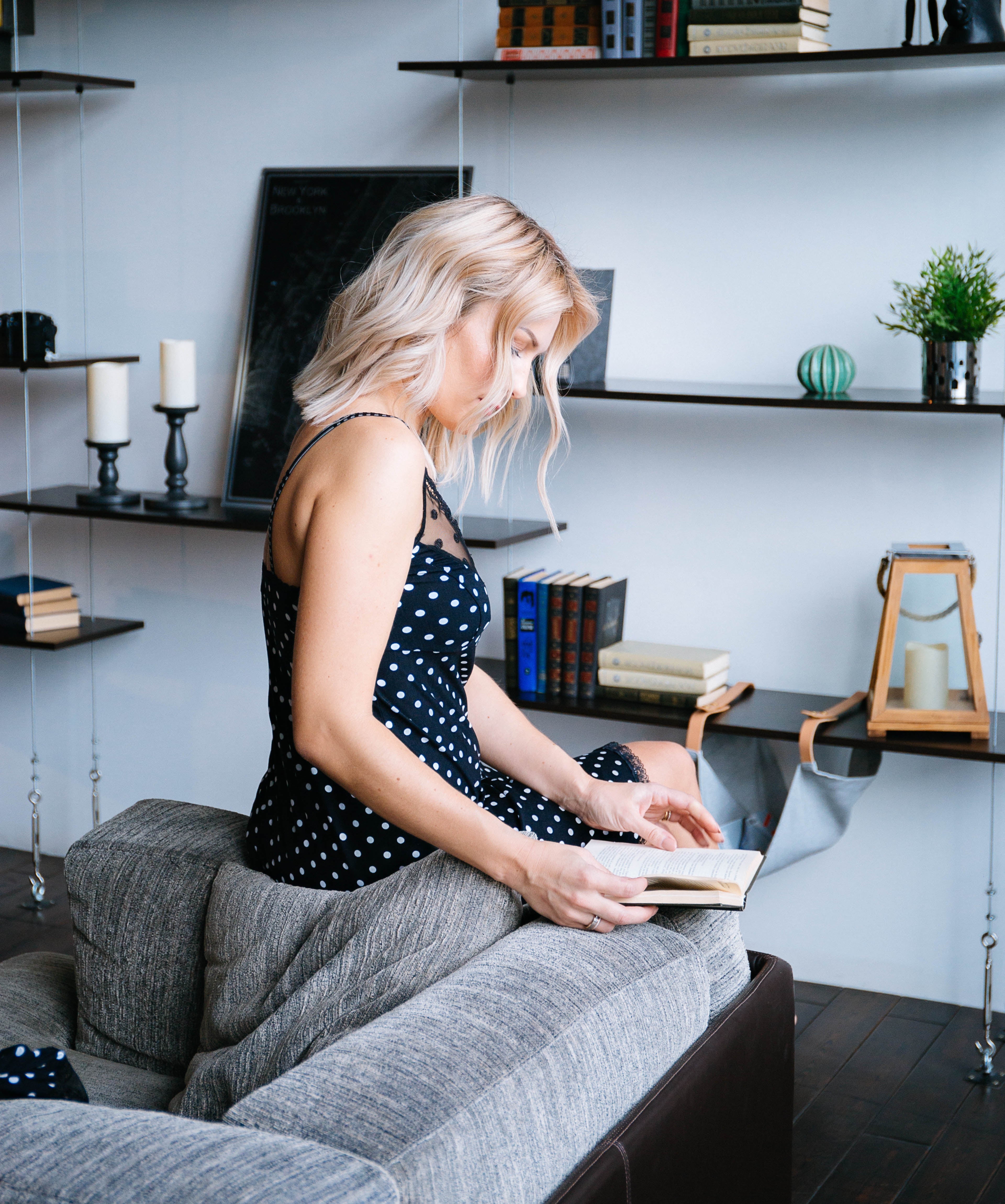 A woman in an elegant home look reading a book on a sofa in a stylish interior — the essence of comfort and femininity with Valmira’s lingerie collection.